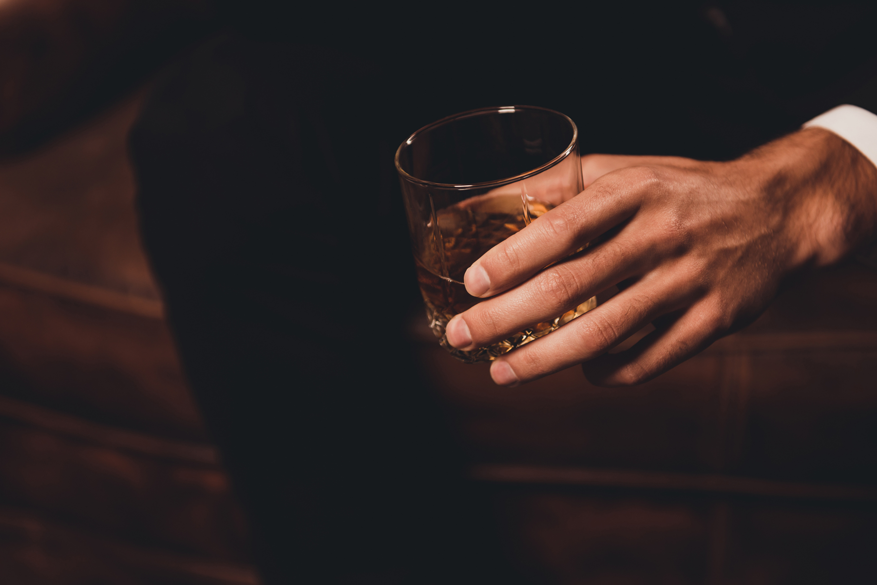 Man's hand holding a glass of whiskey