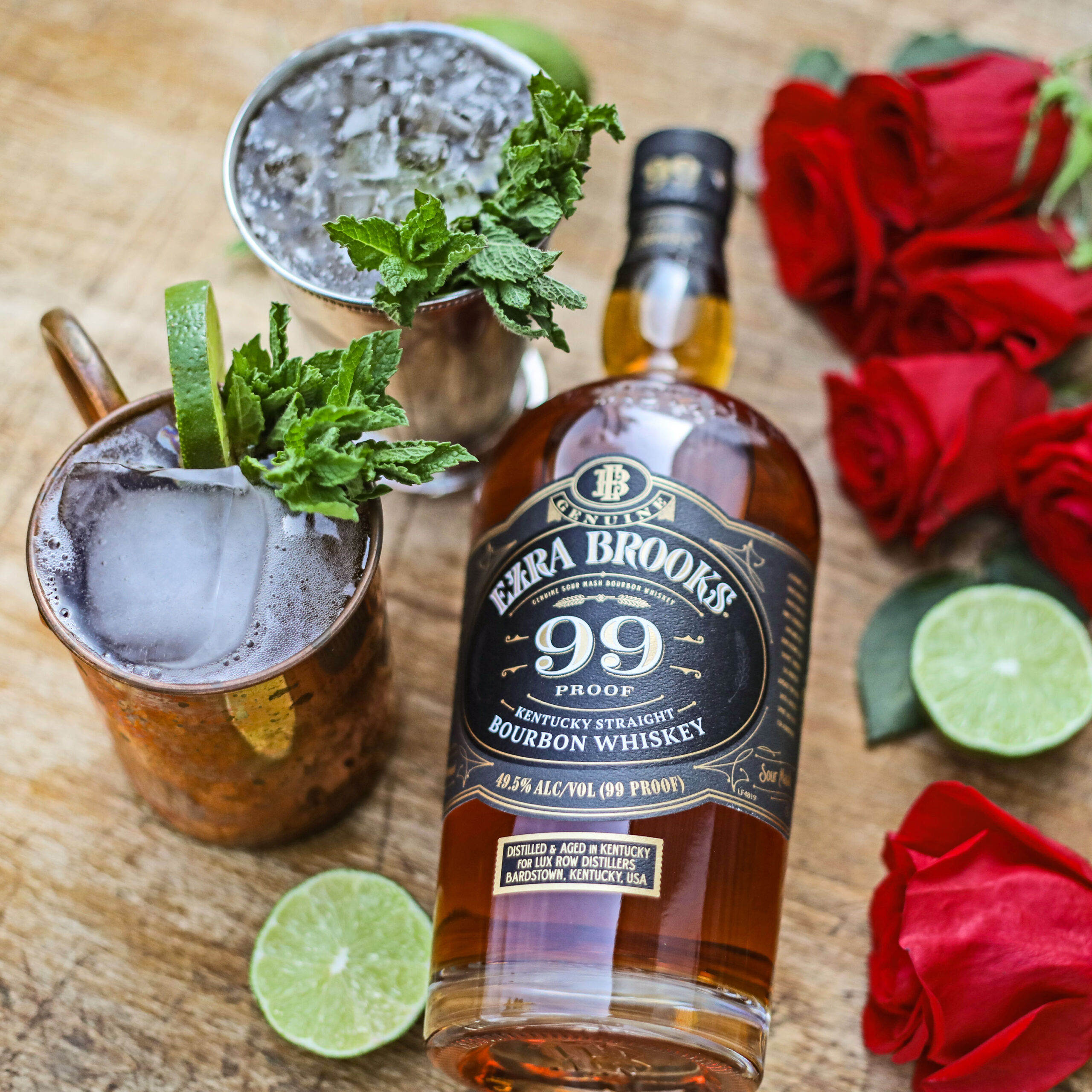 A bottle of Ezra Brooks 99 next to a mint julep cocktail and roses